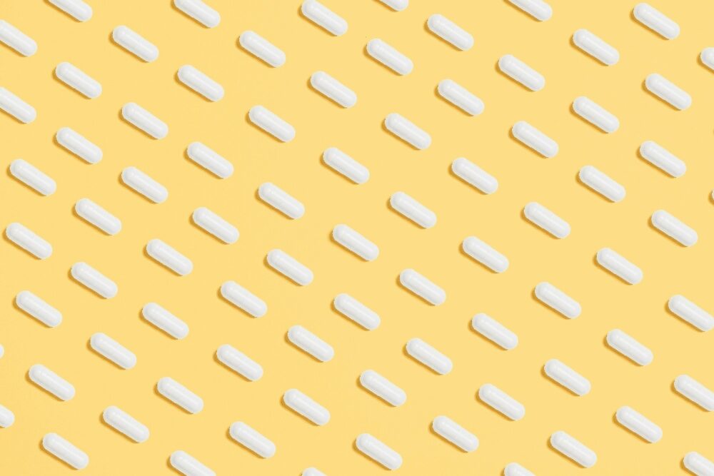 White capsules on a yellow background, symbolising the widespread use of antibiotics and their environmental foot. White capsules on a yellow background, symbolising the widespread use of antibiotics and their environmental foot.